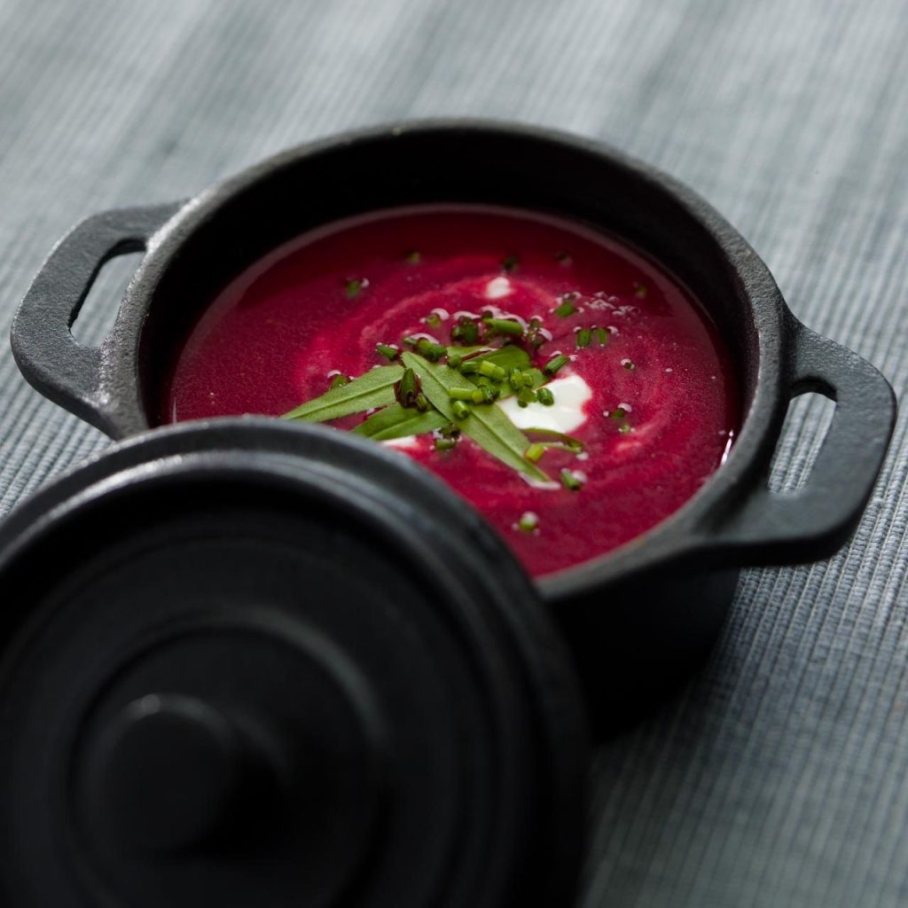 Beetroot soup with sour cream and chives in a small cast-iron pot