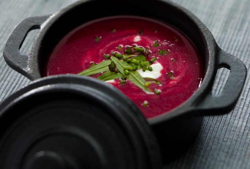 Beetroot soup with sour cream and chives in a small cast-iron pot